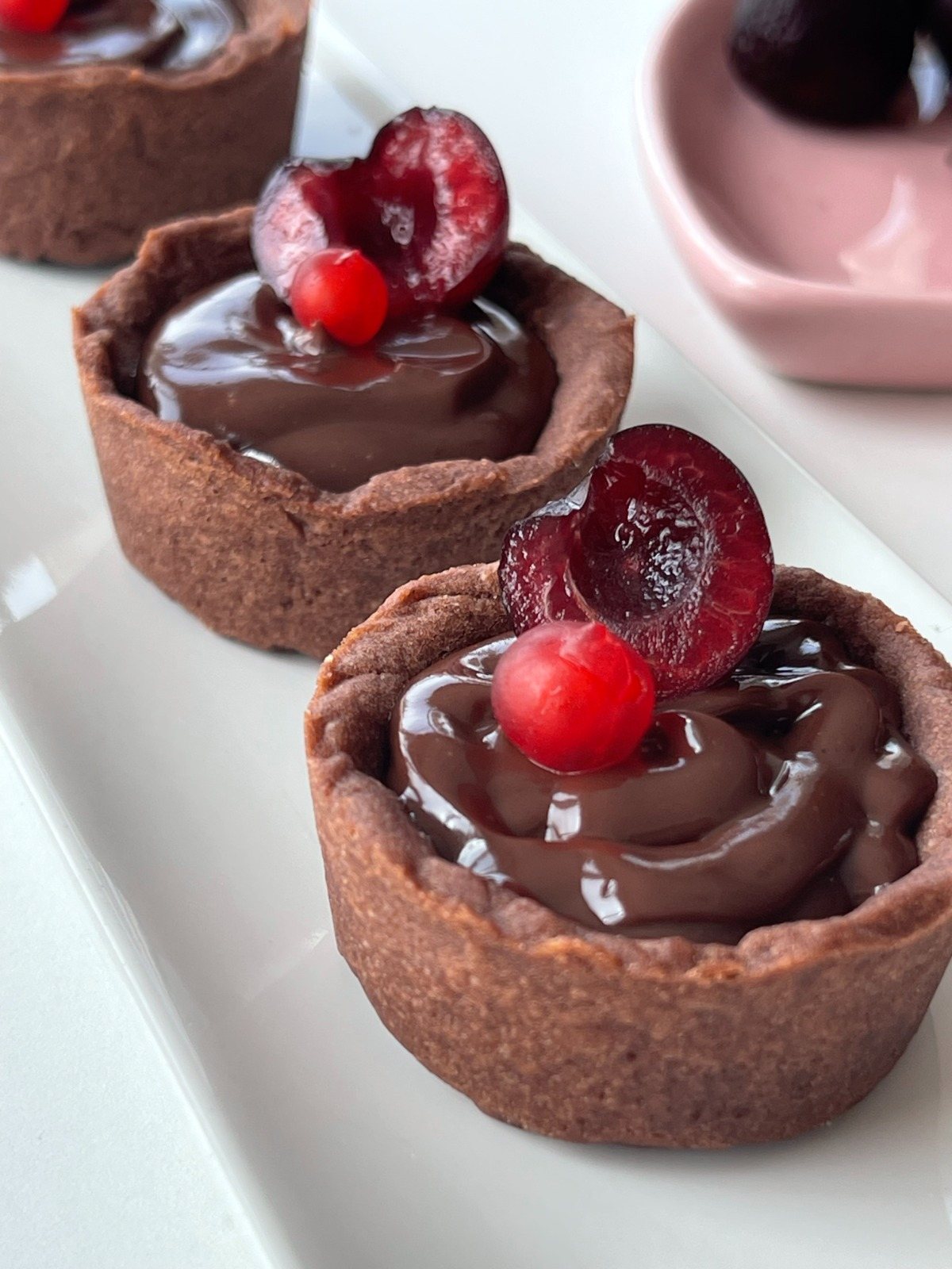 Tartaletas de chocolate con cereza y plato rosa